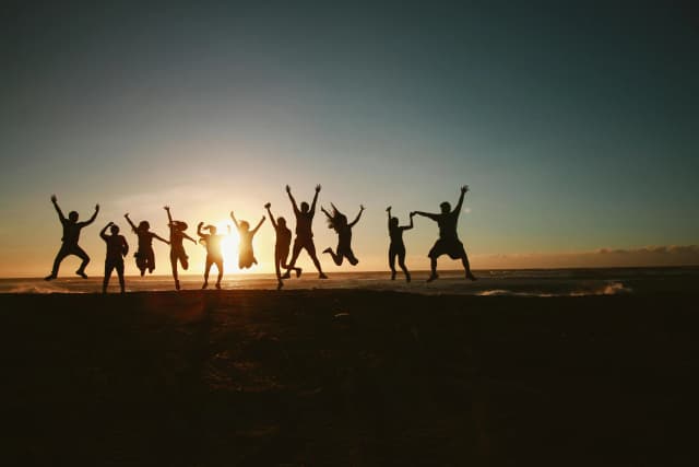 Picture of a group of happy people siloutted against a sunset